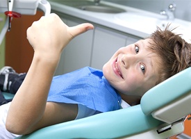 Preteen by in dental chair giving thumbs up