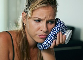 Woman holding ice pack to cheek