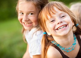 Two little girls laughing outdoors