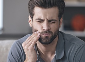 Man grimacing and holding jaw